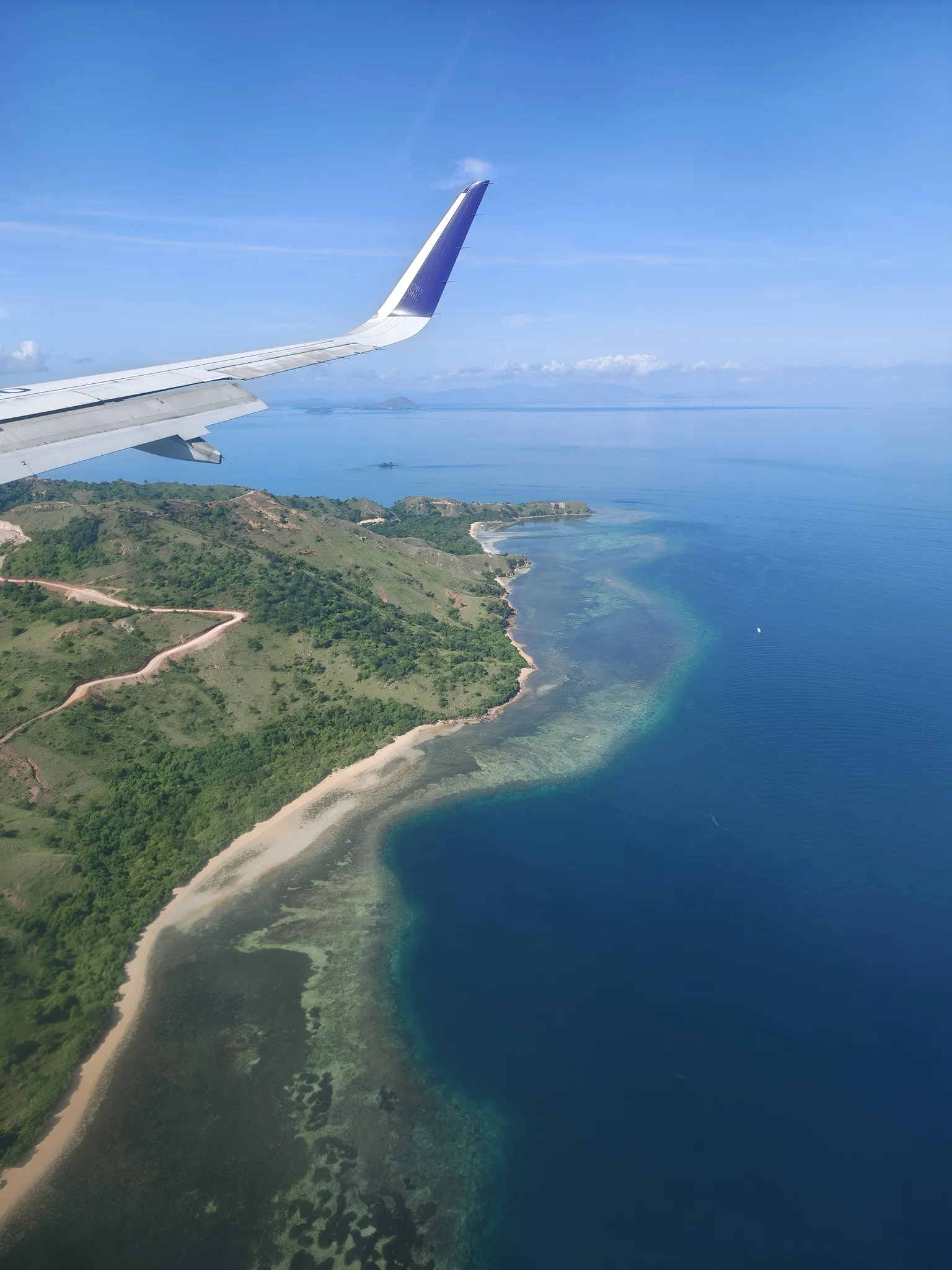 飞机掠过 Seraja-kecil 岛，湛蓝过渡到透明的海水清晰可见